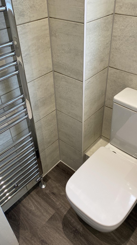 Neat white silicone sealant along tiled bathroom corner and floor-to-wall joint in South Wales