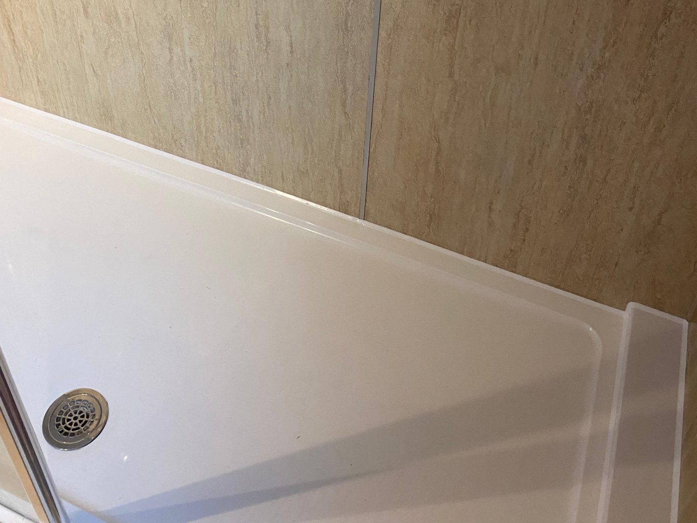 Finished shower tray reseal in South Wales — continuous white silicone along the tray, tiles and waste